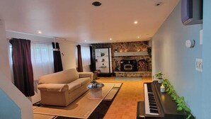Ein Wohnzimmer mit einer Couch, einem Couchtisch, einem Kamin und einem Klavier.