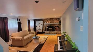 Un salon avec un canapé, une table basse, une cheminée et un piano.