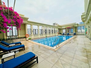 Ein Pool auf dem Dach mit blauen Liegestühlen, einem Rettungsring und Zierpflanzen.
