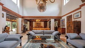 A spacious living room with a glass coffee table, grey sofas, and a chandelier.