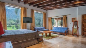 A room with a bed, two sofas, a TV, and a wooden cabinet.