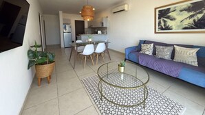 A modern living room with a sofa, coffee table, dining table, chairs, and a kitchen in the background. - Tu Escape Perfecto en Mazatlán by Partner Host (Mazatlán)