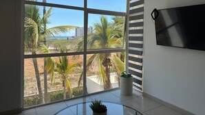 A room with a large window, a flat-screen TV, and a potted plant. - Tu Escape Perfecto en Mazatlán by Partner Host (Mazatlán)