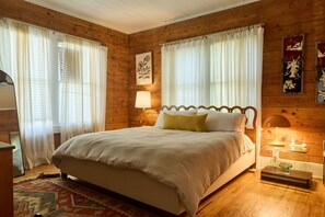 Un dormitorio con paneles de madera, una cama, cortinas, una lámpara y decoración en la pared.
