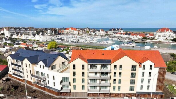 A coastal residential area with multi-story buildings, a marina, and a clear view of the sea. - Le Nid des Bisson - Welkeys (Dives-sur-Mer)