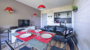 Un espace de vie moderne comprenant un coin repas, un canapé, un téléviseur et un coin cuisine.