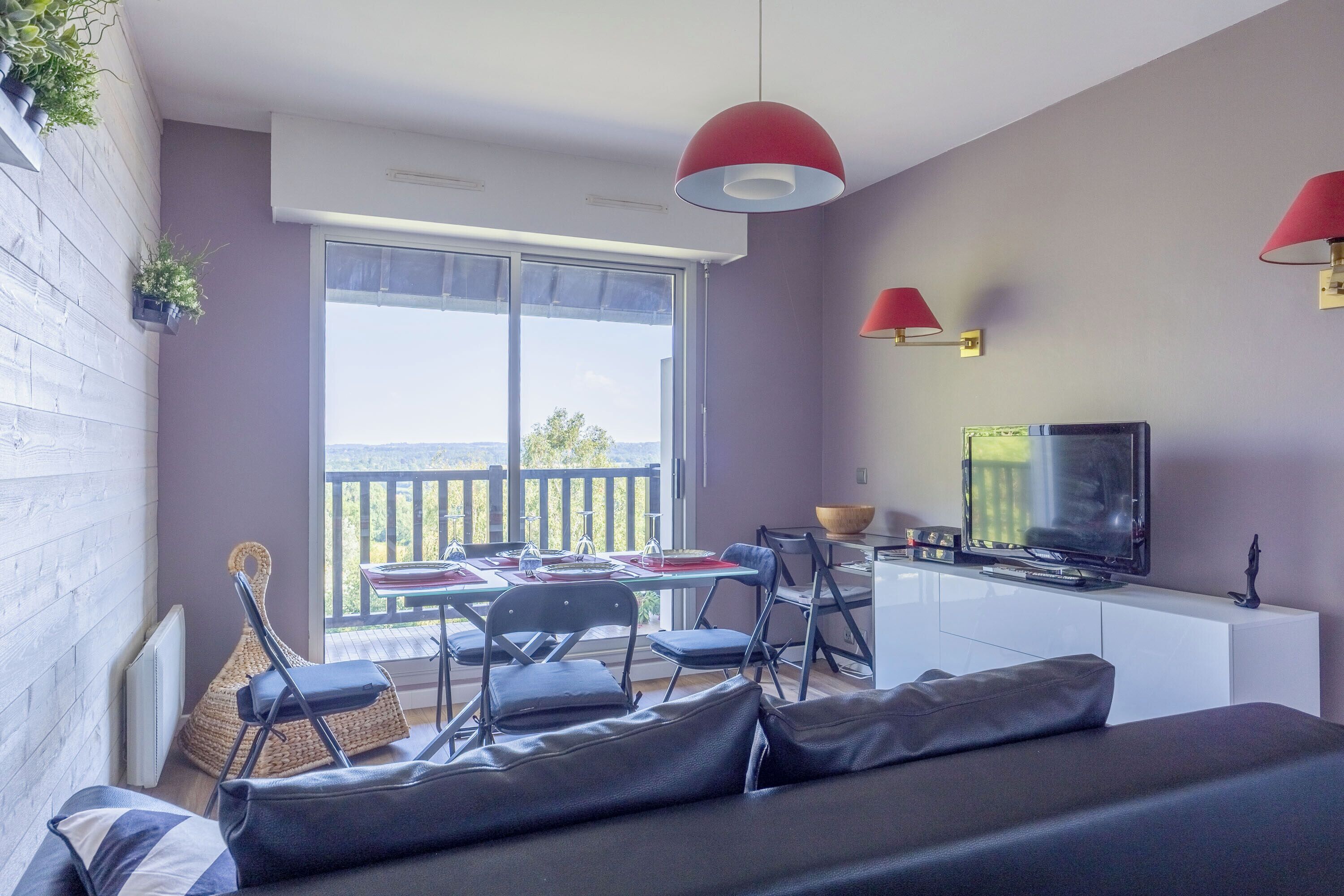 Un salon moderne comprenant un canapé, une table à manger, des chaises, un téléviseur et un balcon avec vue.