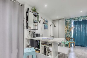 Een moderne kamer met een bureau, kitchenette en zithoek.