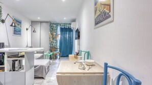 A modern hotel room with a desk, bed, and a dining area with chairs and a table. - Le Jardin du Littoral - Welkeys (Bandol)