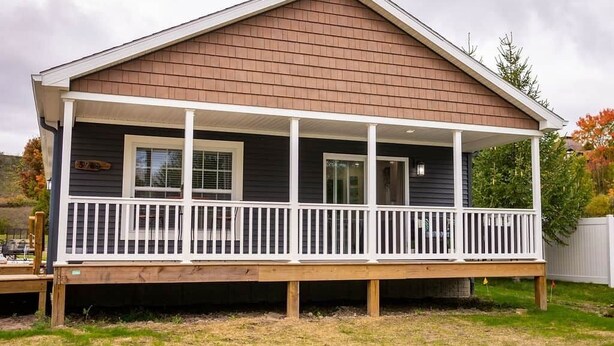 Ein eingeschossiges Haus mit überdachter Veranda und einer kleinen Terrasse.