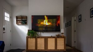 Ein Wohnzimmer mit Flachbildfernseher, Holzschrank, Pflanze und einer Willkommensschild.