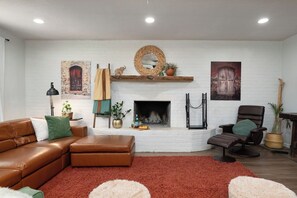 Ein Wohnzimmer mit Kamin, Ledersofa und einem roten Teppich.