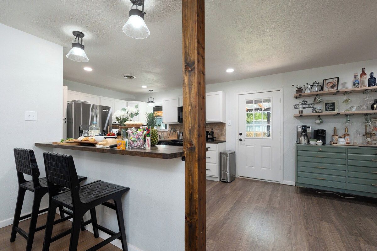 A modern kitchen with a wooden island, bar stools, and a green cabinet with shelves.