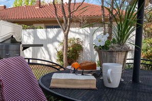 A round table with a book, a mug, a plate with food, and a potted plant. - Ten33 | Luxe Sayles District Experience, King Bed! (Abilene)