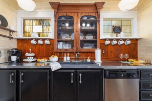 A kitchen with a wooden cabinet, a dishwasher, and a window with a view. - Ten33 | Luxe Sayles District Experience, King Bed! (Abilene)