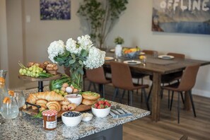 A breakfast buffet with various food items and a decorative vase of flowers on a kitchen island.
