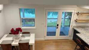 A modern kitchen with a wooden countertop, a dining area with a table and chairs, and a view through a glass door to an outdoor deck. - Charming 3-bedroom house in enjoyable Gig Harbor with AC (Gig Harbor)