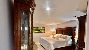 Une chambre à coucher comprenant un lit, une table de chevet, une lampe, une chaise et un grand miroir.