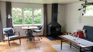 Uma sala de estar com lareira, mesa de jantar, sofá e uma poltrona.