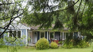 Uma casa com varanda, cercada por grama e árvores.