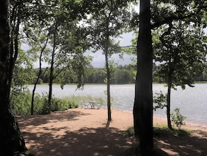 Ein Campingplatz am Seeufer mit Picknicktischen und freiem Blick auf das Wasser.