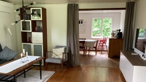 Quarto com uma mesa de jantar, uma cadeira, uma estante de livros, uma televisão e uma janela.