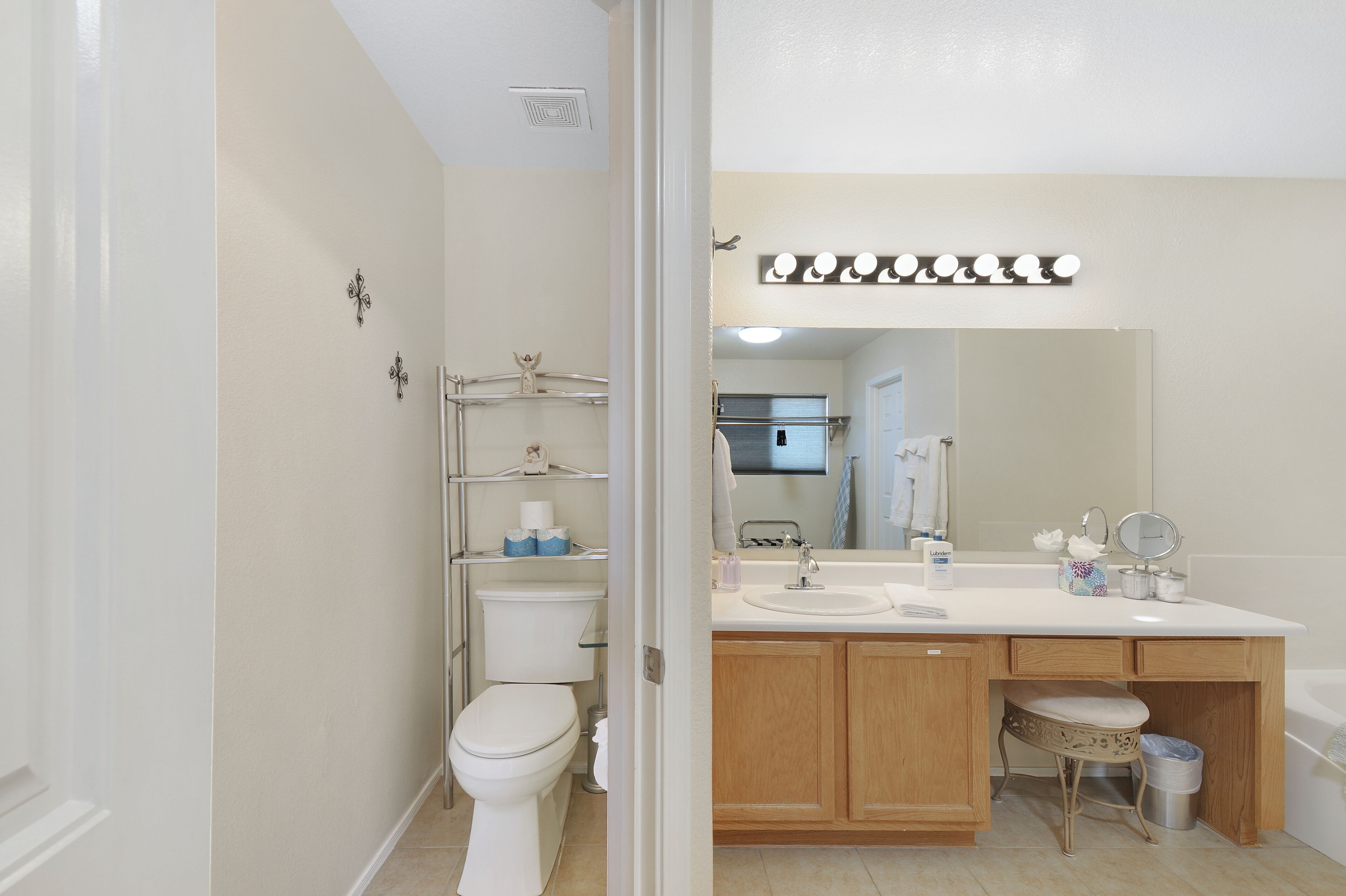 Une salle de bain équipée de toilettes, d’un lavabo, d’un meuble-lavabo et d’un miroir avec des lumières au-dessus.