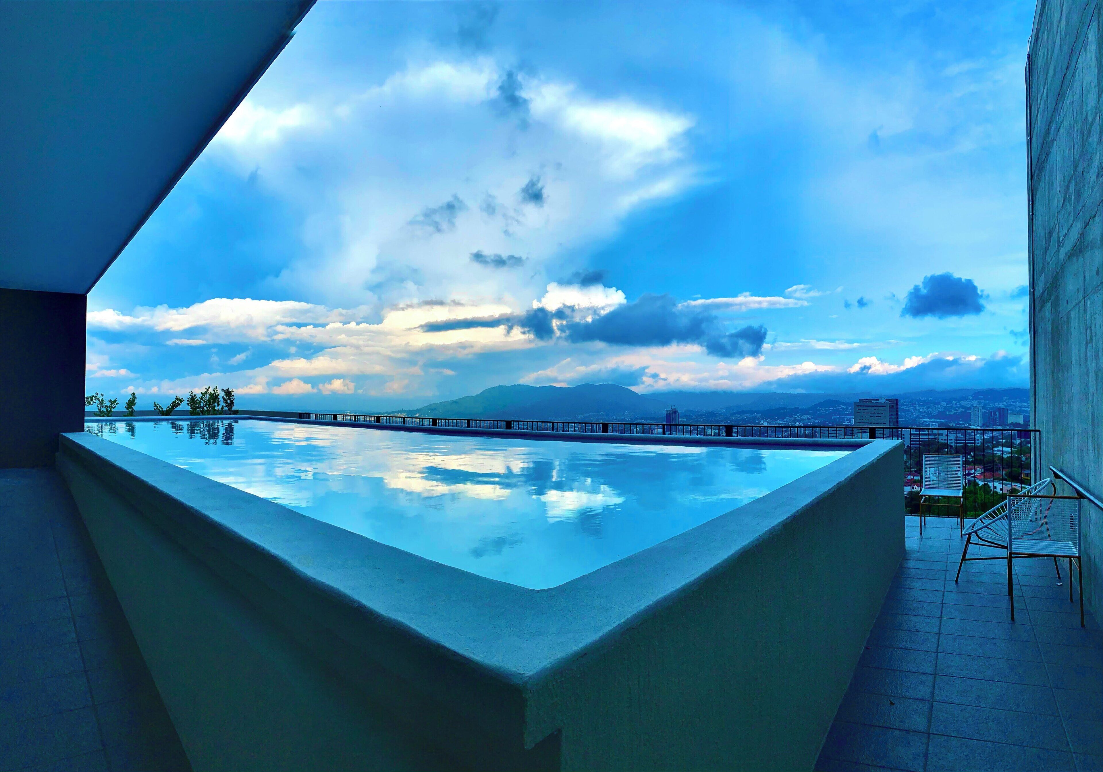 Una piscina en la azotea con vistas a la ciudad, una silla y una mesa.