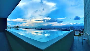 Una piscina en la azotea con vistas a la ciudad, una silla y una mesa.
