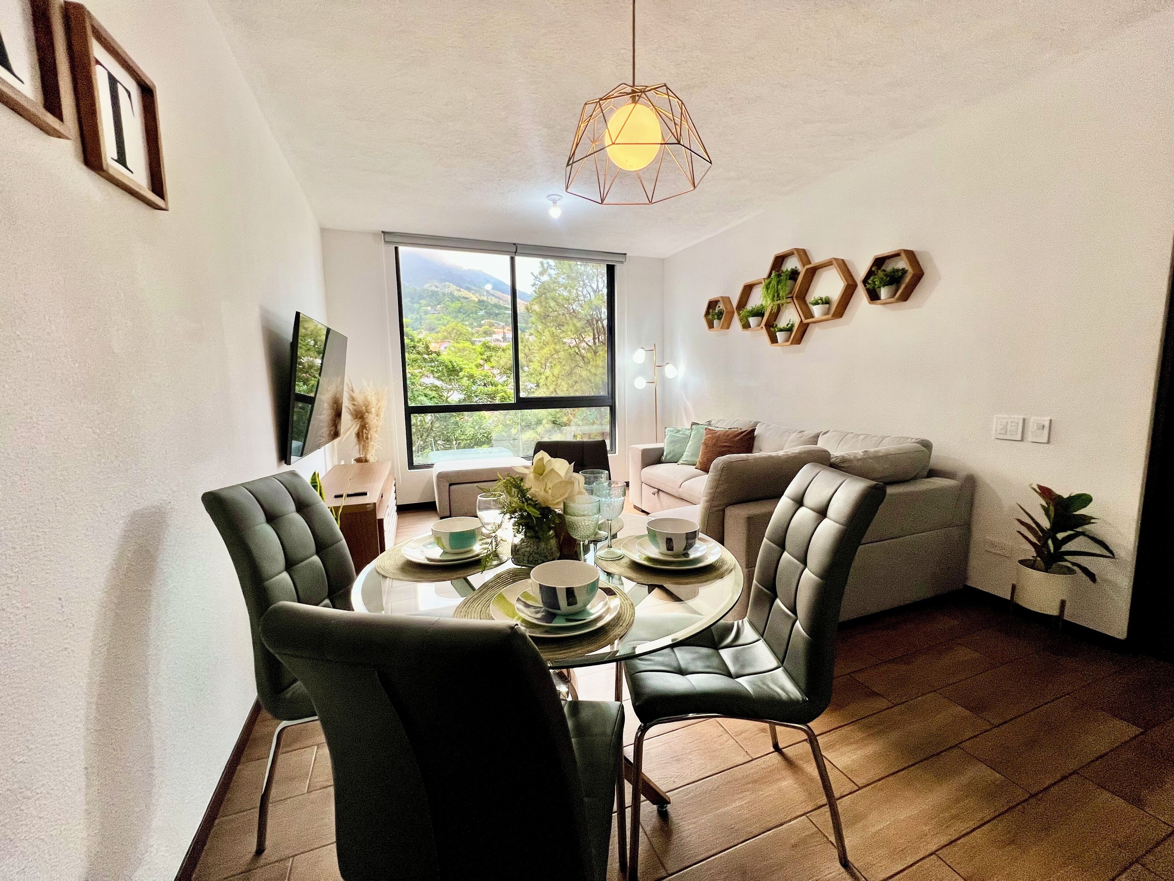 Un comedor con una mesa redonda, sillas y vistas al exterior a través de un ventanal grande.