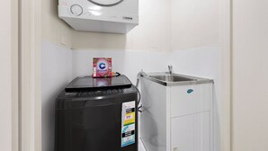 Un espace buanderie compact comprenant un lave-linge à chargement frontal, un sèche-linge et un évier.