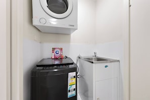 A compact laundry area with a front-loading washer, a dryer, and a sink.