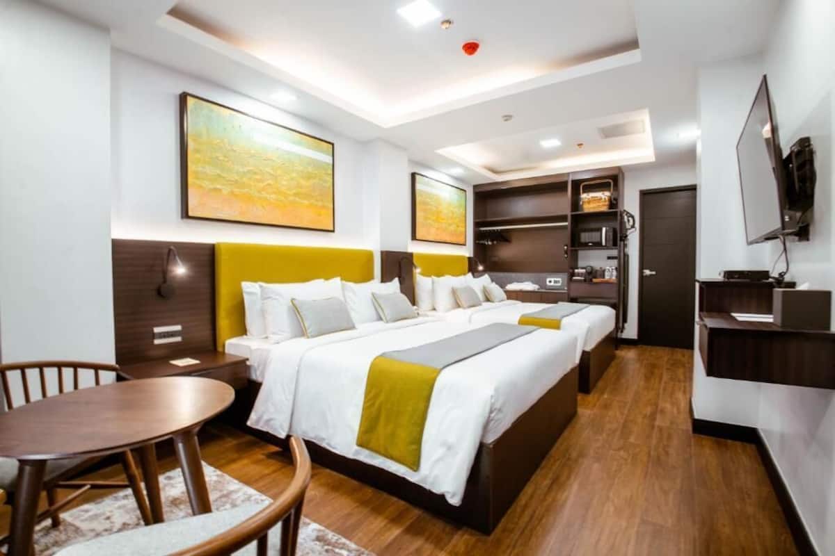 Ein Hotelzimmer mit Bett, Schreibtisch, Stuhl, Fernseher und Bildern an den Wänden.