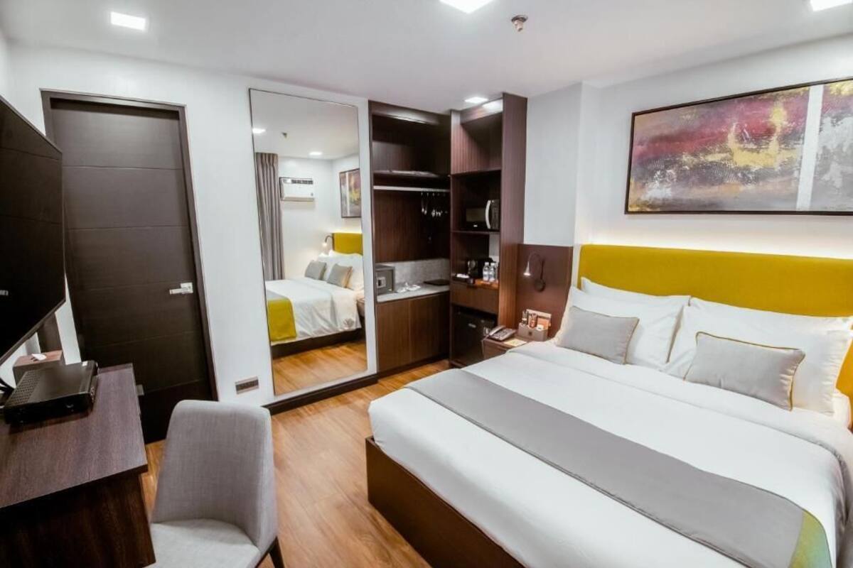 Ein Hotelzimmer mit Bett, Schreibtisch, Stuhl, Kleiderschrank und Spiegel.
