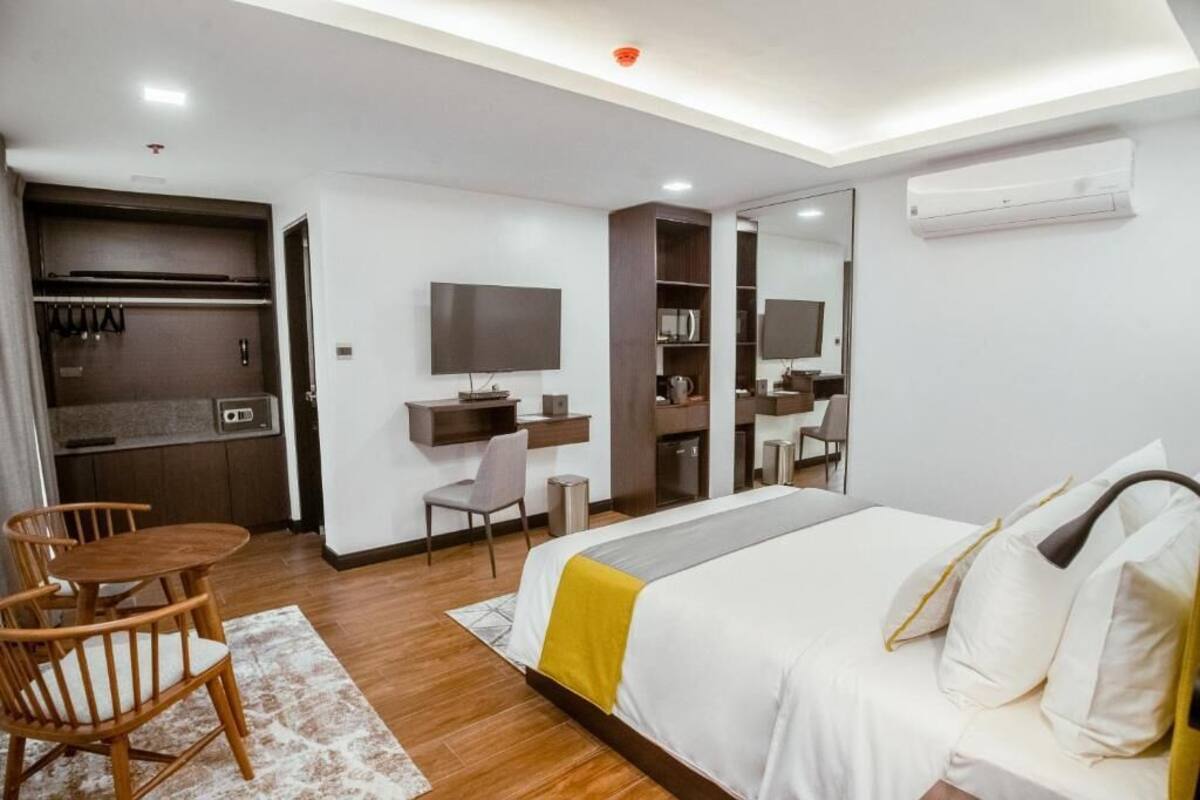 Ein Hotelzimmer mit Bett, Schreibtisch, Stuhl, Fernseher und Kleiderschrank.