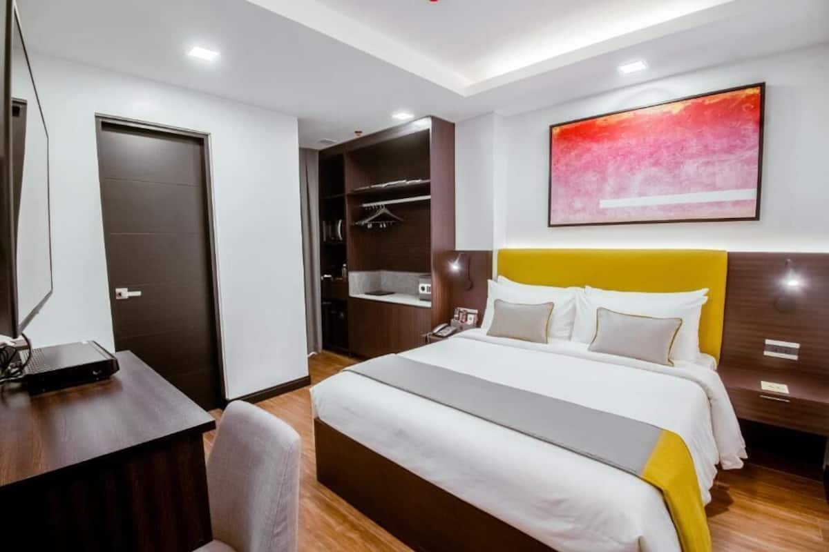 Ein Hotelzimmer mit Bett, Schreibtisch, Stuhl, Kleiderschrank und einem Bild an der Wand.