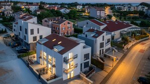 A modern residential area with multi-story buildings, a parking lot, and a road. - House Explorer One (Istria - Funtana) (Funtana)
