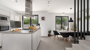 A modern kitchen with a central island, built-in appliances, and a dining area with a table and chairs. - House Explorer One (Istria - Funtana) (Funtana)