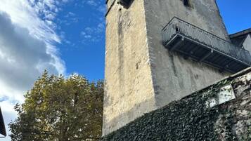 Ein Steinturm mit einem Balkon, umgeben von efeuüberwachsenen Mauern.