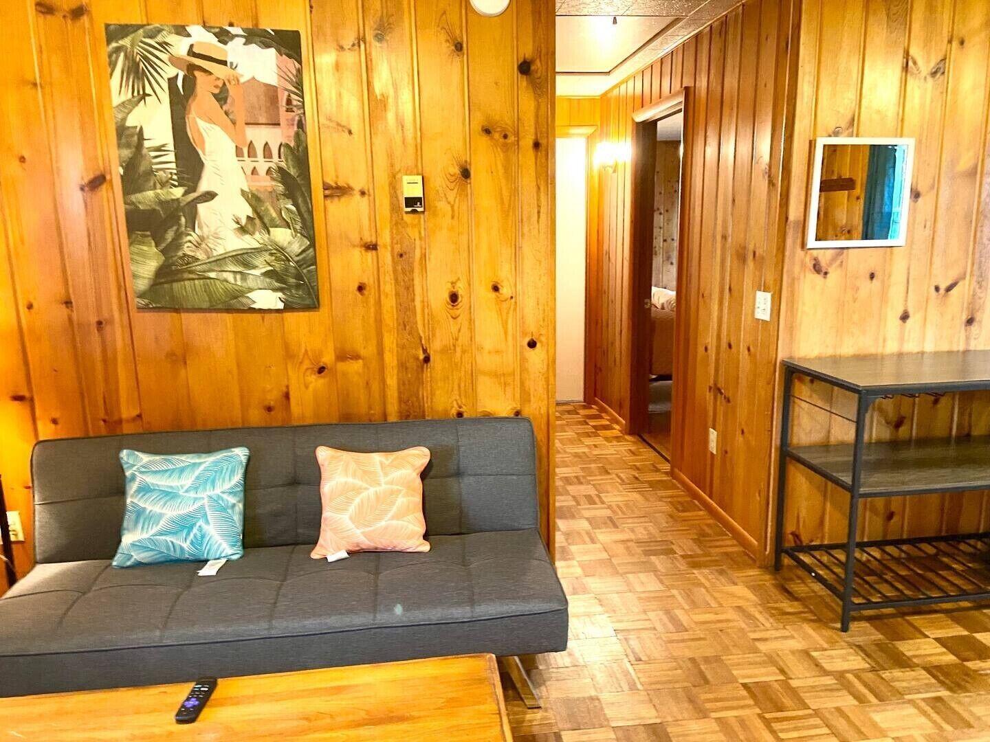 Un interior de madera con un sofá, un control remoto y un espejo.