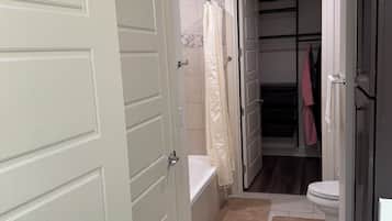 A bathroom with a bathtub, toilet, and a shower curtain.