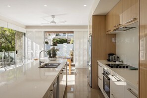 Cozinha moderna com ilha central, eletrodomésticos de aço inoxidável e vista para o exterior.