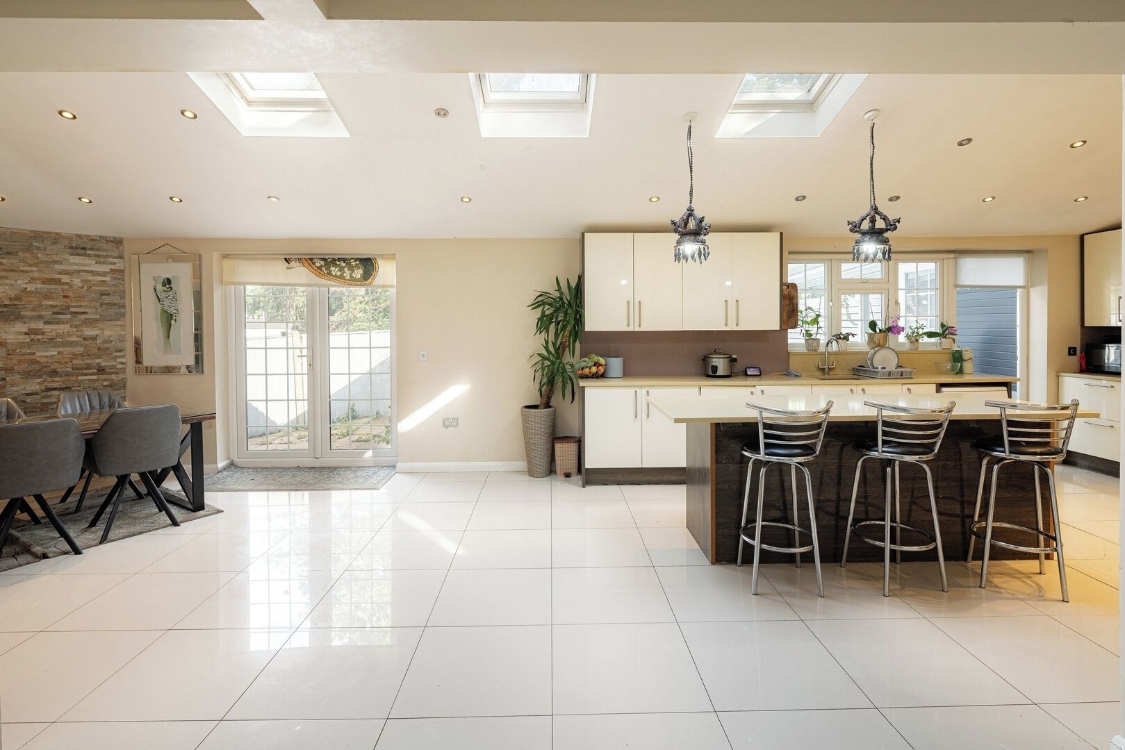 A modern kitchen with a central island, bar stools, and a dining area with a table and chairs.