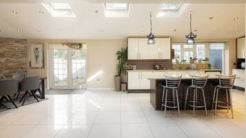 A modern kitchen with a central island, bar stools, and a dining area with a table and chairs.