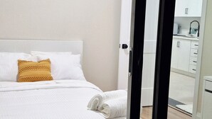 Un dormitorio con una cama, un cojín amarillo y una cama bien tendida.