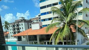 Blick aus einem Fenster auf eine Straße mit abgestellten Motorrädern, einem weißen Auto und Häusern mit roten Ziegeldächern.