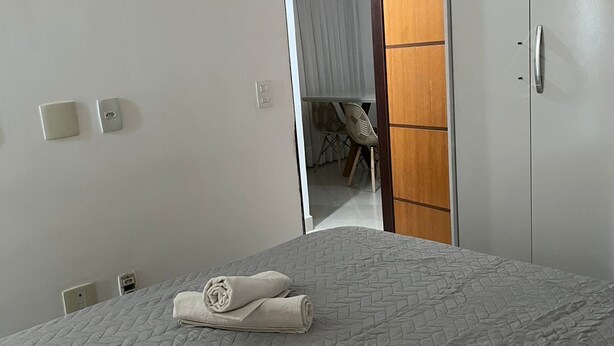 Ein Hotelzimmer mit Bett, Kleiderschrank, Klimaanlage und einem durchgegangenen Tür erkennbaren Badezimmer.
