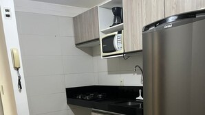 Eine kleine Küche mit einem Edelstahl-Kühlschrank, einer Mikrowelle und einem Gasherd.