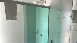 Ein Badezimmer mit Duschkabine, Toilette und Waschbecken inklusive Spiegel.