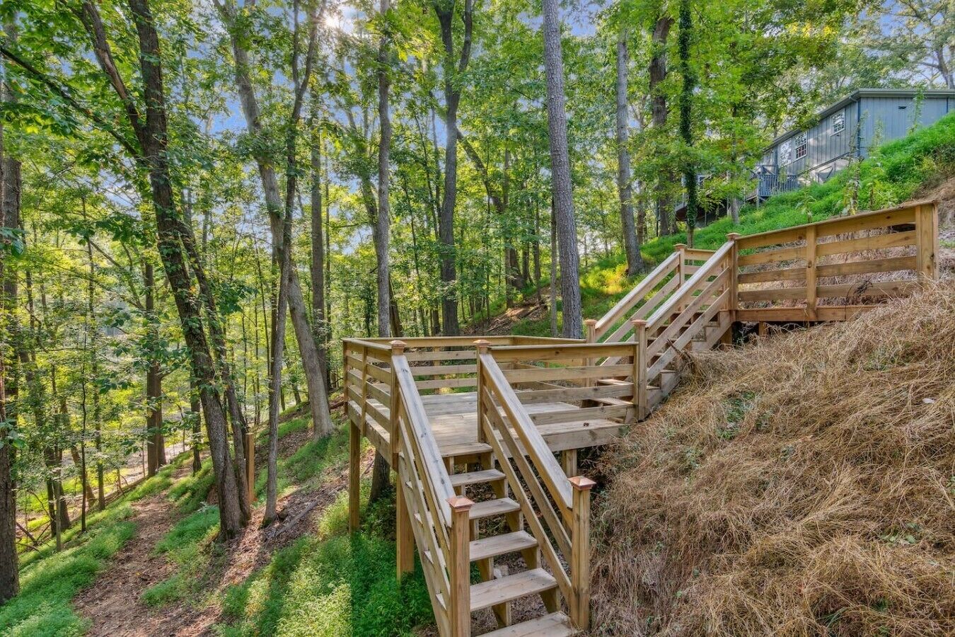 Wooden staircases in a forested area with a building in the background.